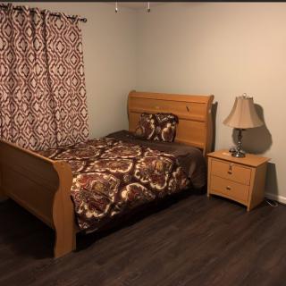 A cozy bedroom with a wooden bed and nightstand, featuring patterned bedding and curtains.