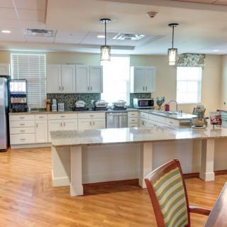 A modern kitchen interior with white cabinets, countertops, and wooden flooring.