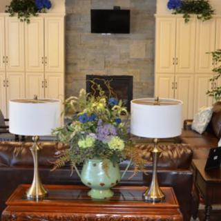 A beautifully decorated living room featuring a central table with ornate flowers and elegant lamps.