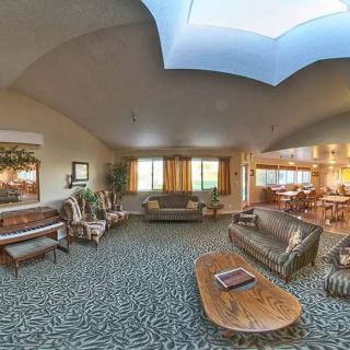A spacious living room with comfortable seating, carpeted floors, and a skylight that brightens the space.