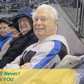 A group of elderly individuals seated at a stadium event.