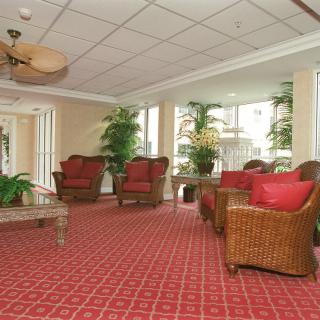 A comfortable hotel lobby with wicker furniture and vibrant red carpet.