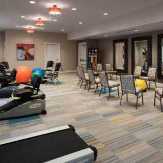 A spacious gym area equipped with exercise machines, therapy balls, and chairs for fitness activities.