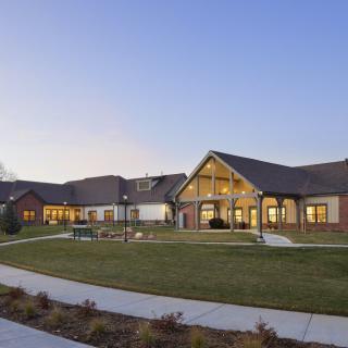 A suburban residential building at sunset with a well-maintained lawn and pathway.