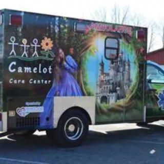 An ambulance decorated with a fantasy-themed design, featuring a castle and the name 'Camelot Care Center'.
