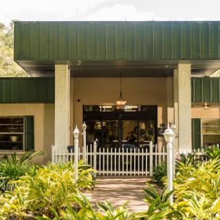 A charming building with a green metal roof and welcoming entrance, surrounded by lush landscaping.