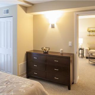 A cozy modern bedroom with a dark wood dresser and soft lighting.