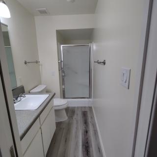 A modern bathroom with a shower, sink, and toilet.
