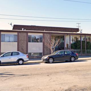 A street view of a small, one-story commercial building with parked cars in front.