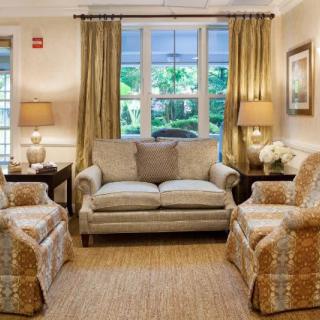 A cozy living room with a sofa, two armchairs, and warm lighting.