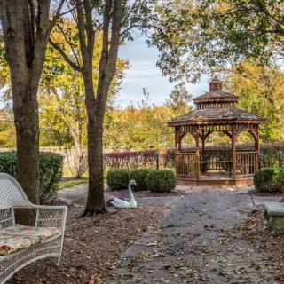 A tranquil garden scene with a gazebo, surrounded by trees and autumn foliage.