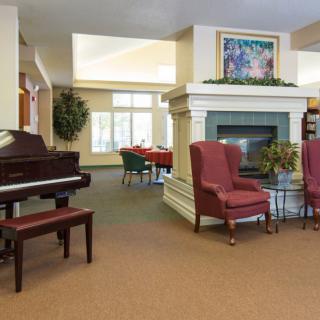 A cozy lounge interior featuring a piano and a fireplace with seating.