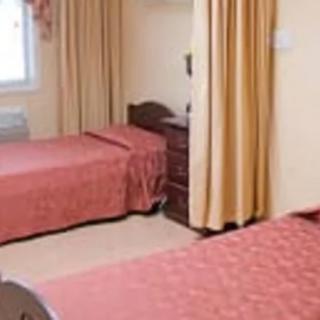 A simple hotel room with two twin beds and muted decor.