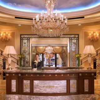 Luxurious hotel lobby with a grand chandelier and elegant reception desk.