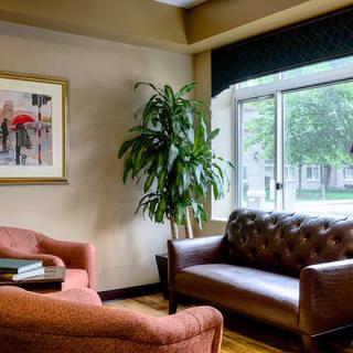 A cozy living room with a sofa, armchair, and a large window letting in natural light.