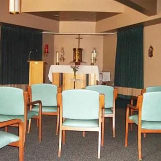 A small chapel interior with chairs arranged facing the altar.