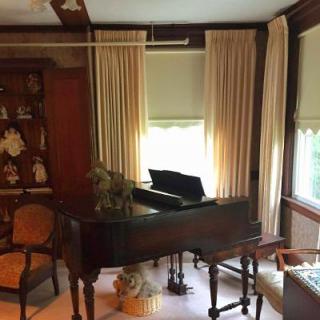 A serene living room featuring a grand piano, elegant curtains, and classic wooden furniture.