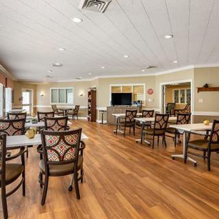 A spacious and modern dining area with wooden floors, multiple tables, and chairs arranged neatly.