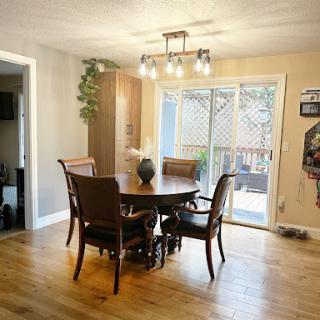 A cozy dining area featuring a round table and elegant chairs, illuminated by a stylish light fixture, with access to an outdoor space through a sliding door.