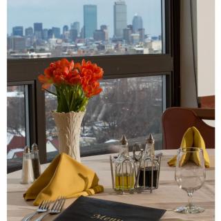A restaurant table elegantly set with a view of the urban skyline through the window.