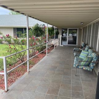 A cozy porch area with seating, surrounded by a garden.