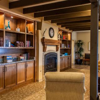 A warm and inviting living room featuring elegant wood beams, a charming fireplace, and built-in bookshelves filled with books.
