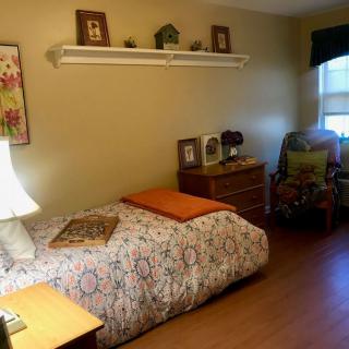 A cozy bedroom with a single bed, wooden furniture, and decorative elements.