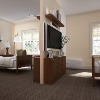 A cozy bedroom with double beds, a central TV unit, and ample natural lighting.