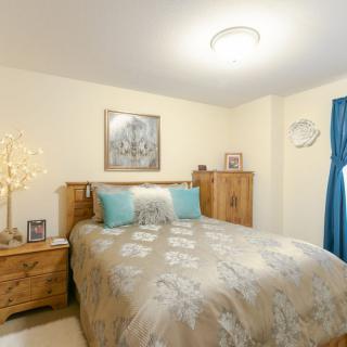 A cozy bedroom with a wooden bed and matching furniture, decorated with a painting and a unique lamp.