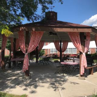An outdoor gazebo with red curtains and patio furniture.