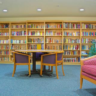A cozy library space with shelves full of books and a small table surrounded by chairs.