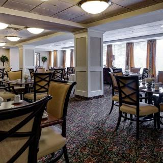 A well-lit restaurant interior featuring neatly arranged tables and chairs on a patterned carpet.