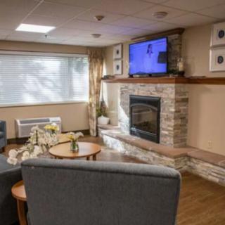 A cozy living room features a stone fireplace, modern furniture, and a wall-mounted television.