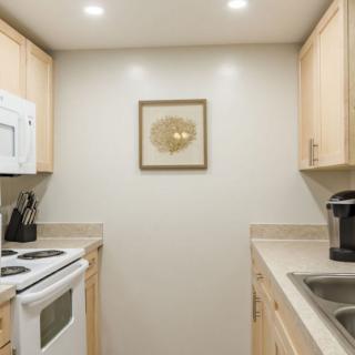 A compact modern kitchen with light wood cabinets and essential appliances.