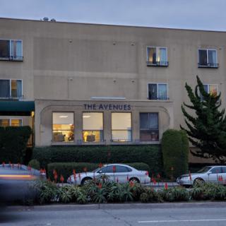 A view of a residential building at dusk, showcasing its architecture and nearby greenery.