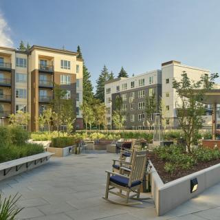 A modern residential complex featuring landscaped gardens and outdoor seating.