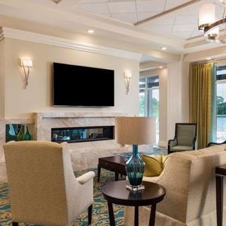A modern living room with comfortable seating, a television mounted above the fireplace, and decorative lighting.