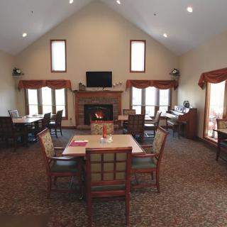 A cozy living room with a fireplace, tables, and chairs arranged for a communal setting.