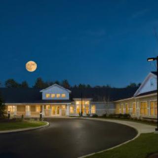 A well-lit building with a circular driveway under a clear night sky and a full moon.