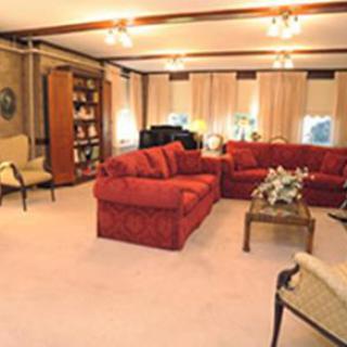 A cozy living room featuring a red sofa set, a bookshelf, and warm lighting.