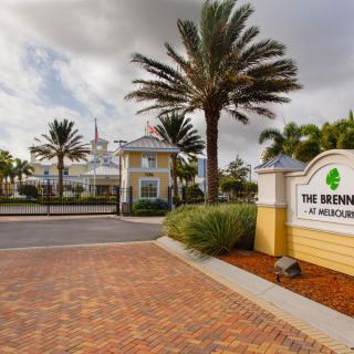 Entrance to a resort with palm trees and a welcoming sign.