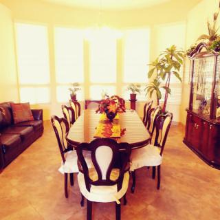 A well-lit dining room with a large table and chairs, adorned with floral decorations.