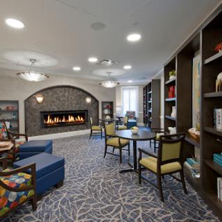 A cozy lounge area featuring a fireplace, comfortable seating, and bookshelves, perfect for relaxation.