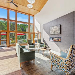 A beautifully designed lounge area featuring large windows that invite natural light and a serene view of the outdoors.