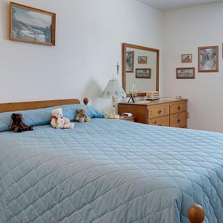 A cozy bedroom with blue bedding, decorated with stuffed animals and framed pictures.