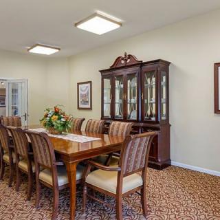 A traditional dining room with a long wooden table, surrounded by chairs and featuring a china cabinet in the background.