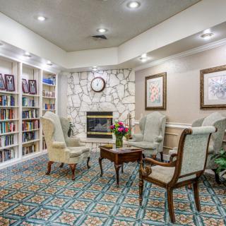 A cozy library seating area with a fireplace surrounded by bookshelves and comfortable chairs.