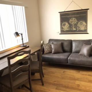 A cozy living room with a leather sofa, desk, and wall art.