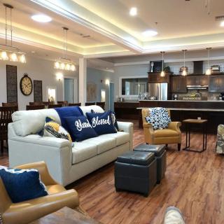 A modern living room and kitchen area with comfortable seating, stylish decor, and warm wood flooring.