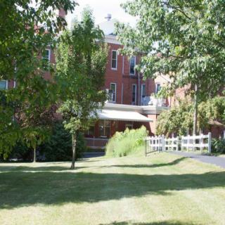 A brick residential building surrounded by trees and grass.